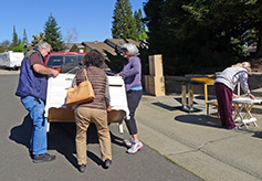 Volunteers help to load a dresser onto a truck